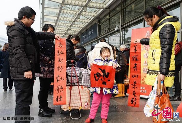  2015年2月4日，为期40天的2015年春运大幕正式开启。当日也恰逢立春时节，上海铁路局文联的艺术家们在铁路上海站南广场，为即将踏上返乡旅途的旅客们现场免费书写春联，送上新春祝福。图为旅客拿到春联在晾干墨迹。中国网图片库 赖鑫琳/摄